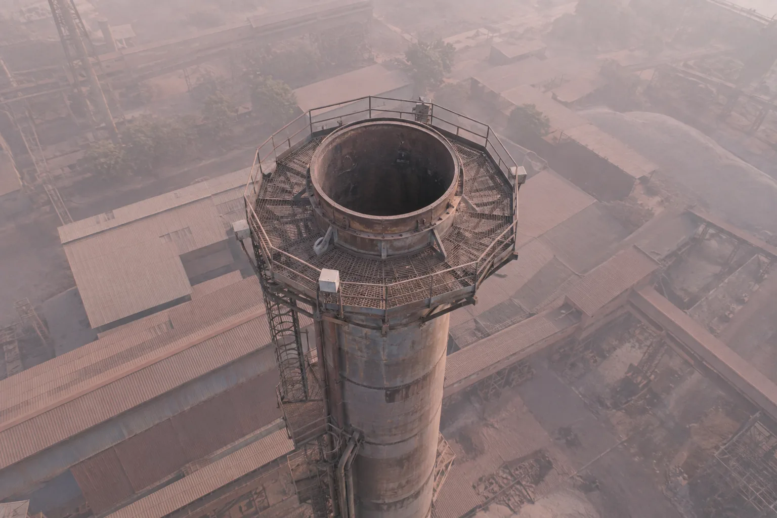 A stack top seen through pinkish-grey plant dust haze